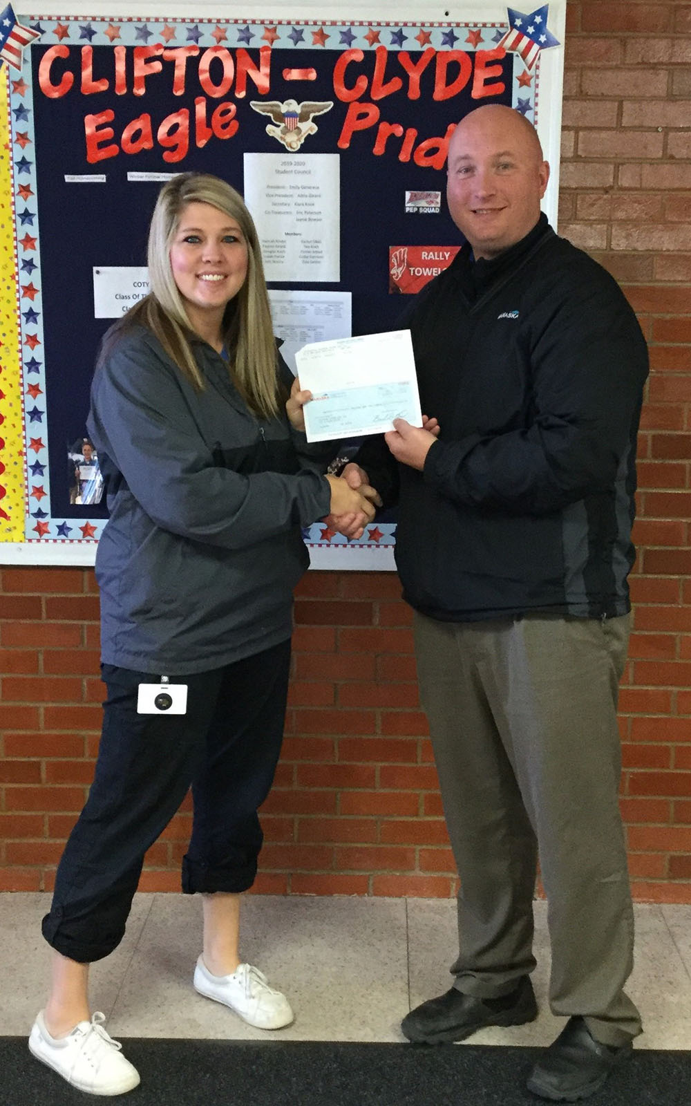 Two people at a school holding a check